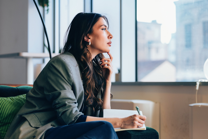 Thoughtful Businesswoman Writing Notes in a Modern Office Space