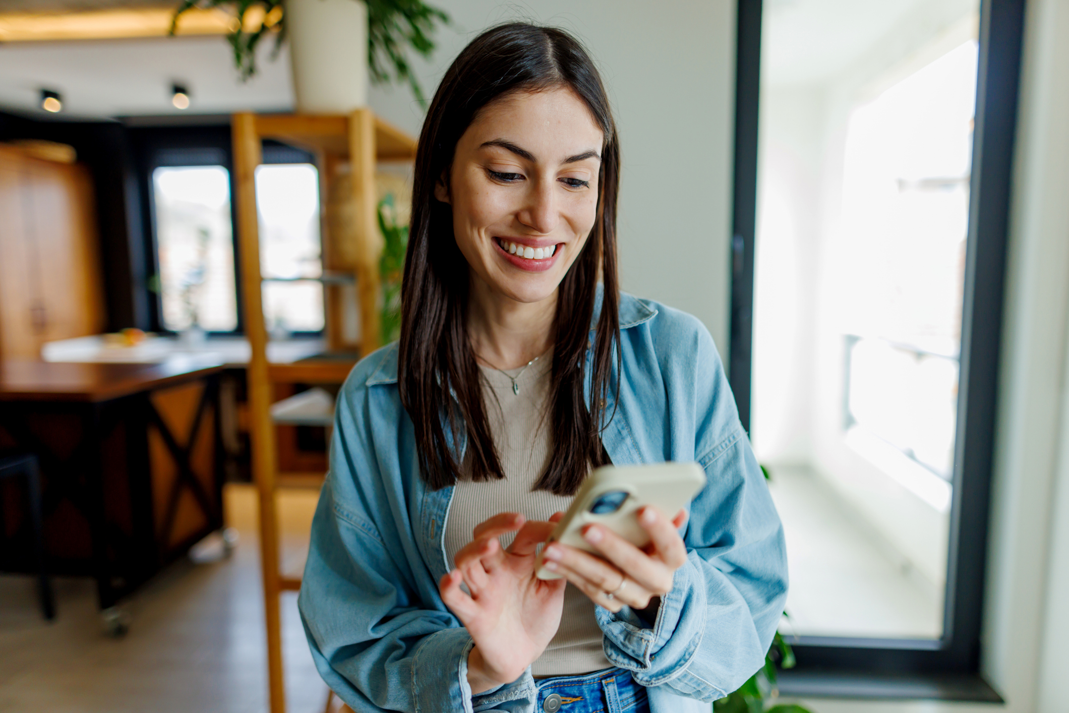 Young Adult Woman Engaging with Smartphone Indoors