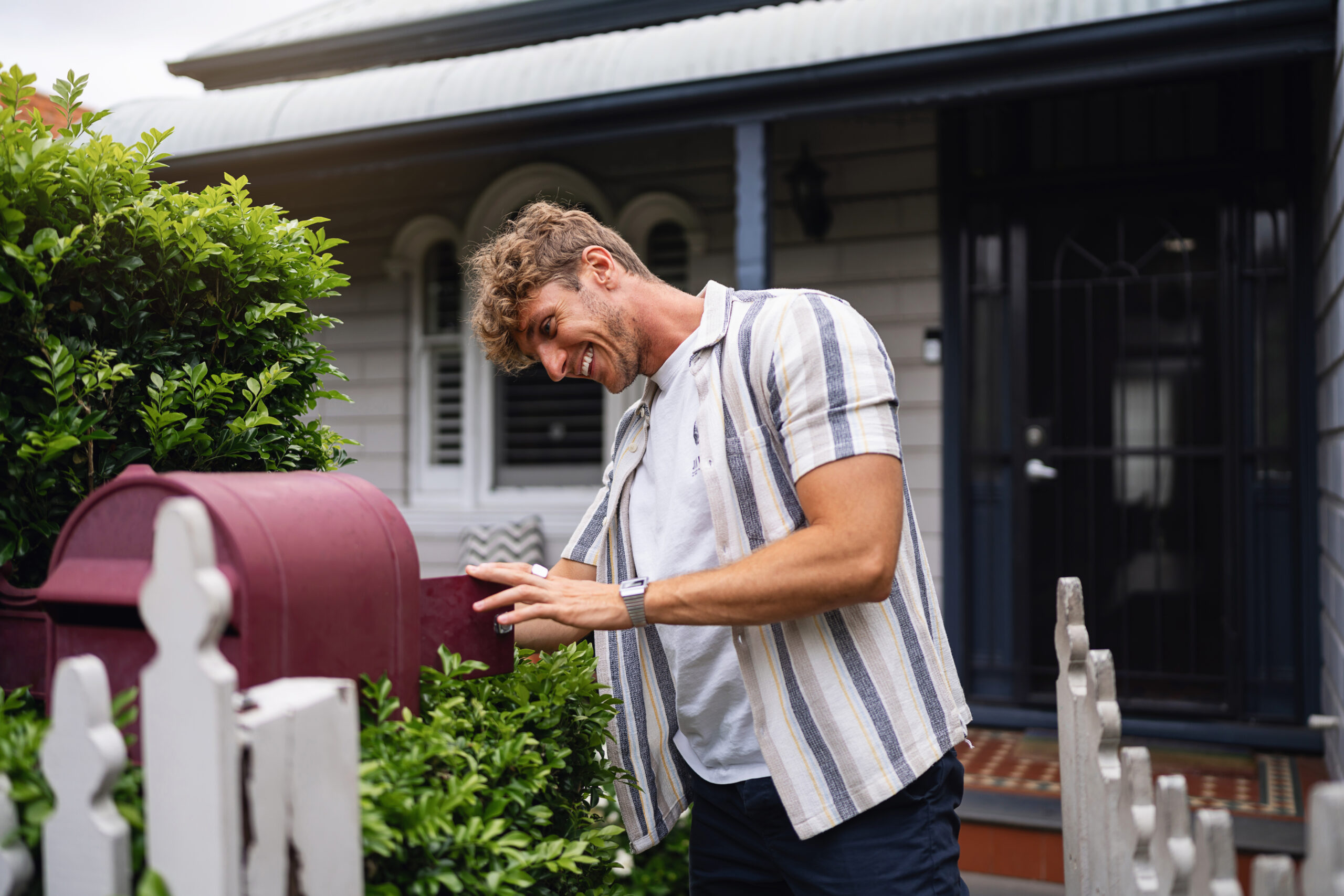 Young Man Checking Mail Outside a Cozy Suburban Home